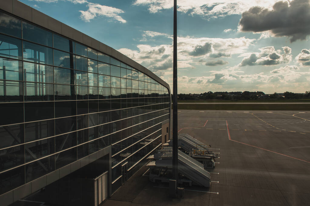 Fachada de vidro do aeroporto com aeródromo e céu nublado ao fundo em Copenhague, Dinamarca
  - Foto, Imagem