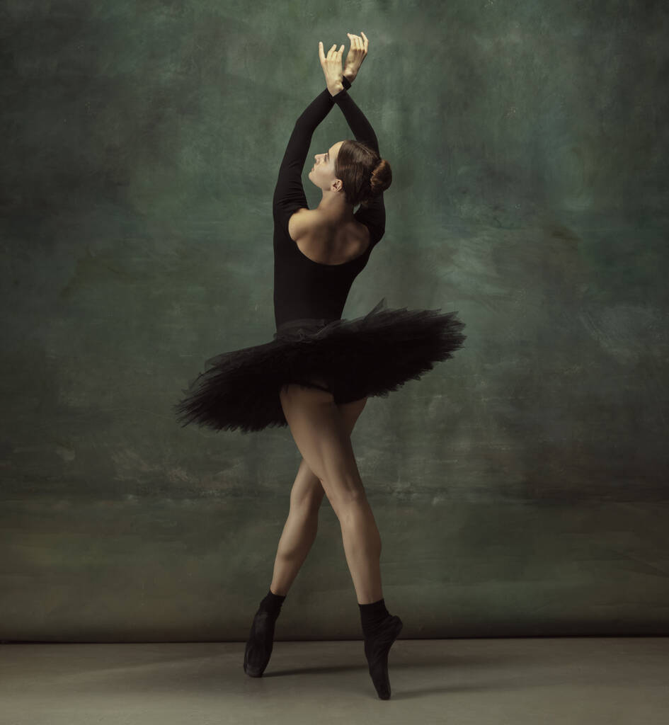 Karanlık stüdyo geçmişinde zarif genç bir balerin. - Fotoğraf, Görsel