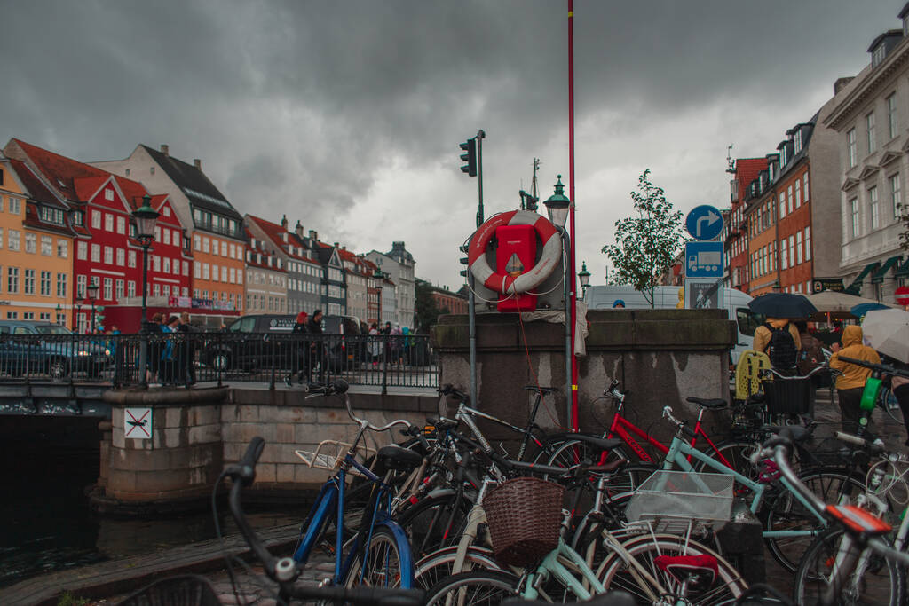 COPENHAGEN, DENMARK - 30 ΑΠΡΙΛΙΟΥ 2020: Ποδήλατα κοντά σε κανάλι στο λιμάνι Nyhavn με συννεφιασμένο ουρανό στο βάθος  - Φωτογραφία, εικόνα