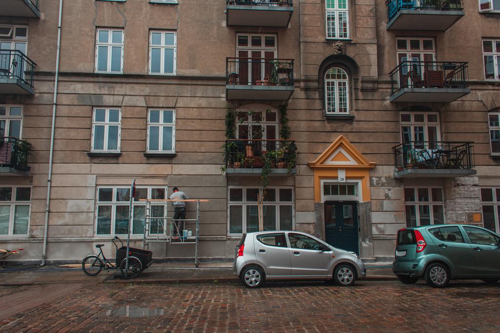 Danimarka 'nın Kopenhag kentsel caddesindeki binanın ön cephesinde otomobiller görülüyor.  - Fotoğraf, Görsel