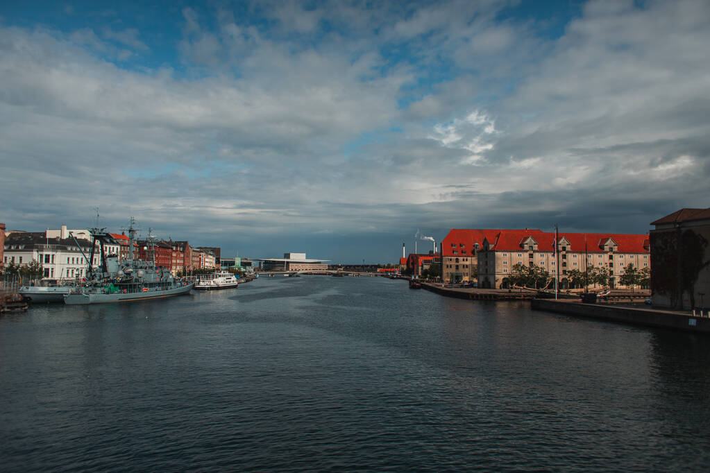 Edifícios perto do canal e barcos no porto com céu nublado no fundo em Copenhague, Dinamarca
  - Foto, Imagem