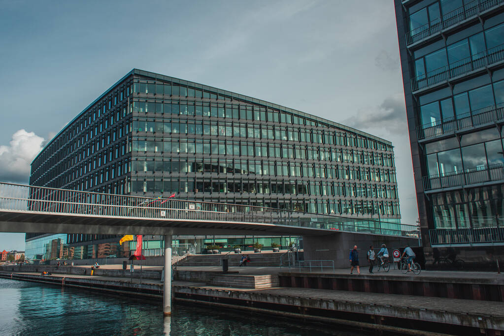 COPENHAGEN, DÁNIA - Április 30, 2020: Emberek kerékpárok közelében híd és épületek a városi utcán a háttérben - Fotó, kép