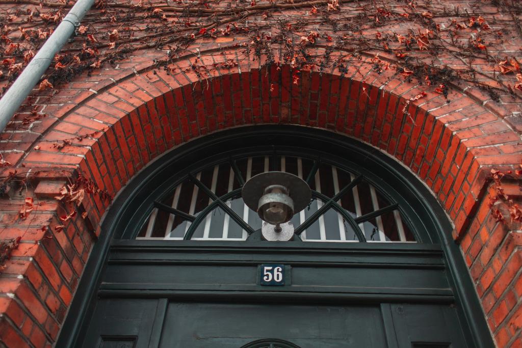 Niedriger Winkel Ansicht der Laterne in der Nähe von Tür und Werk auf Ziegelfassade des Gebäudes in Kopenhagen, Dänemark  - Foto, Bild