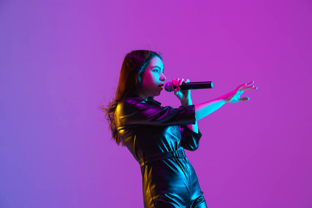 Ritratto di cantante caucasica isolato su sfondo viola studio in luce al neon
 - Foto, immagini