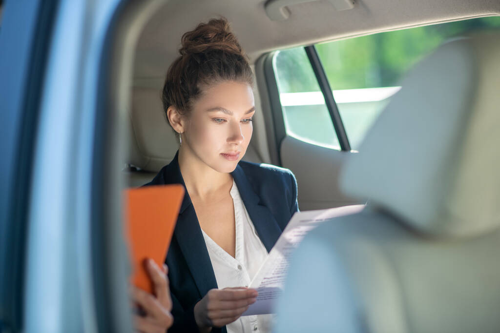 Mujer de negocios seria estudiando un documento en un coche
. - Foto, imagen