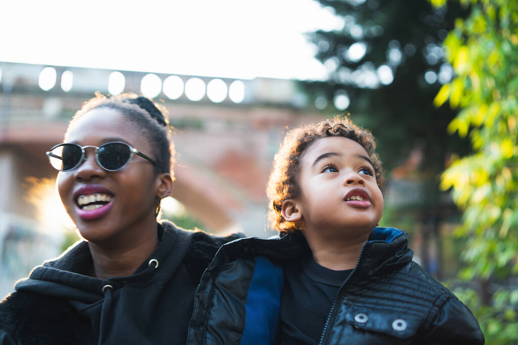 Porträt einer afroamerikanischen Mutter mit ihrem Sohn, der draußen im Park steht und Spaß hat. Monoparentenfamilie. - Foto, Bild