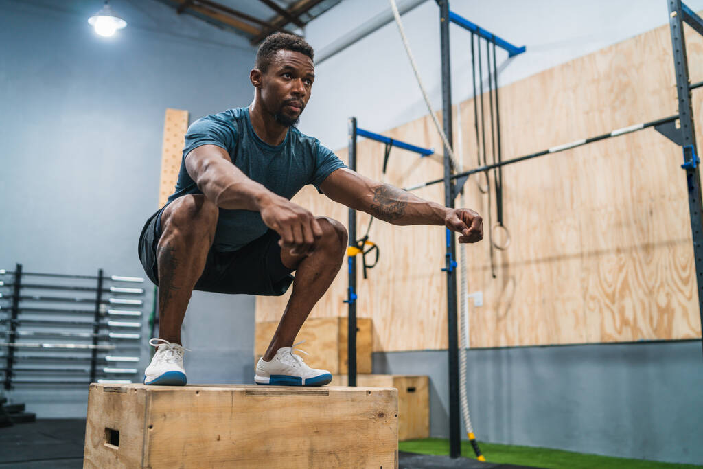 Retrato de un hombre atlético haciendo ejercicio de salto de caja. Crossfit, deporte y estilo de vida saludable concepto. - Foto, imagen