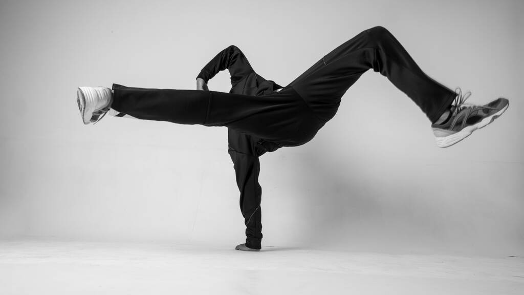 Человек, танцующий хип-хоп или bboy замерзает в одной позе на белом фоне. Bboy делает стильные трюки
. - Фото, изображение