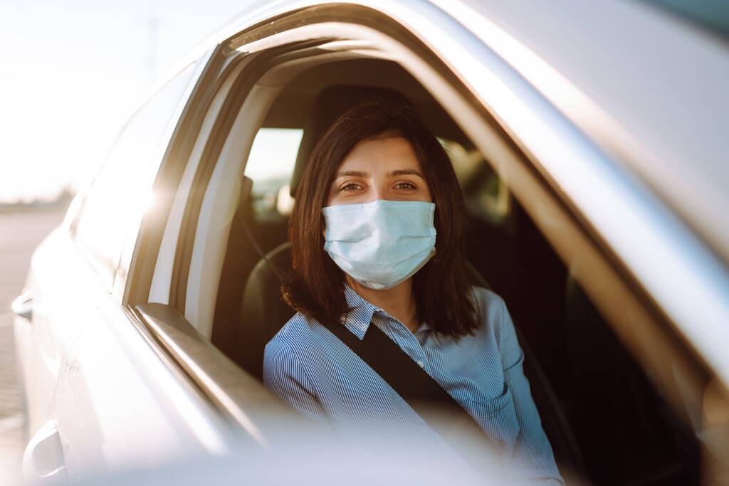 Meisje passagier in beschermende steriele medische masker in de taxi auto tijdens een epidemie in quarantaine stad. Gezondheidsbescherming, veiligheid en pandemie Covidius - 19.  - Foto, afbeelding