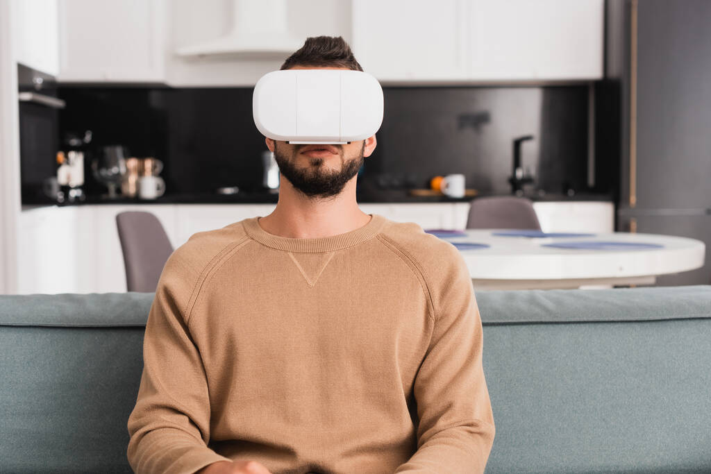 homem barbudo em realidade virtual headset sentado na sala de estar
  - Foto, Imagem