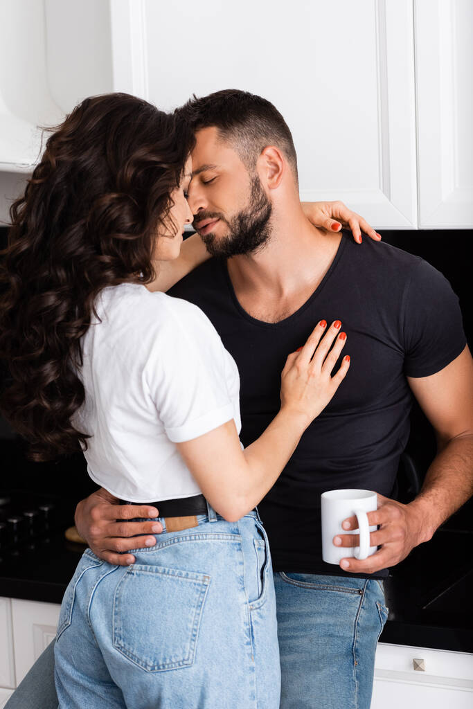jovem mulher abraçando barbudo homem com xícara de café
 - Foto, Imagem