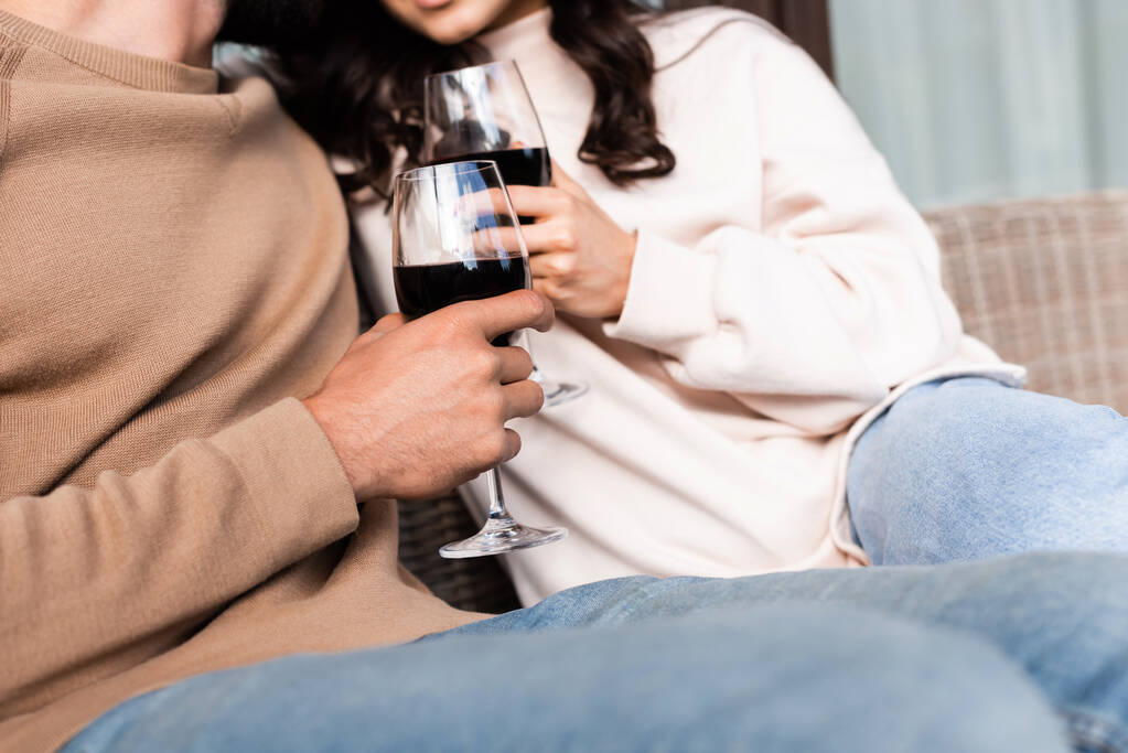 καλλιεργημένη άποψη της γυναίκας και του άνδρα κρατώντας ποτήρια κόκκινο κρασί έξω  - Φωτογραφία, εικόνα