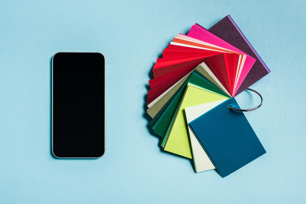 Vista superior del teléfono inteligente y muestras de color en la superficie azul
 - Foto, imagen
