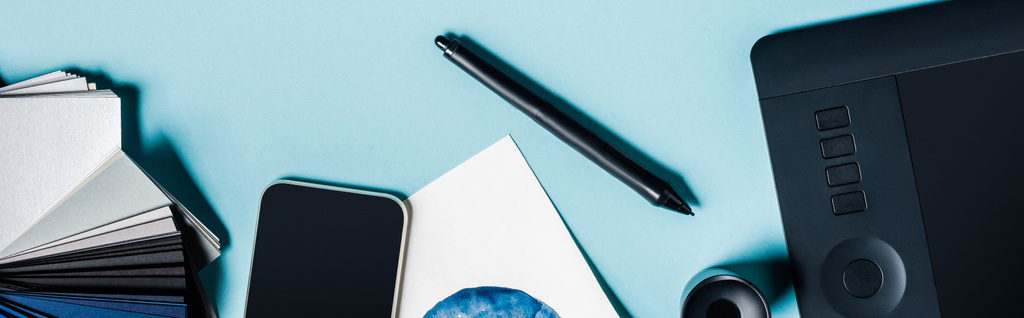 青の背景にグラフィックタブレット、スマートフォンやカラーサンプルのパノラマショット - 写真・画像