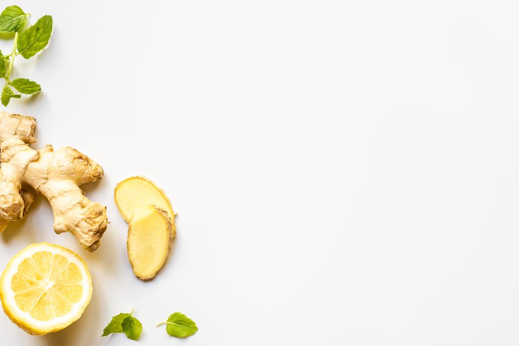 Beyaz arkaplanda zencefil kökü, limon ve nane yapraklarının üst görünümü - Fotoğraf, Görsel