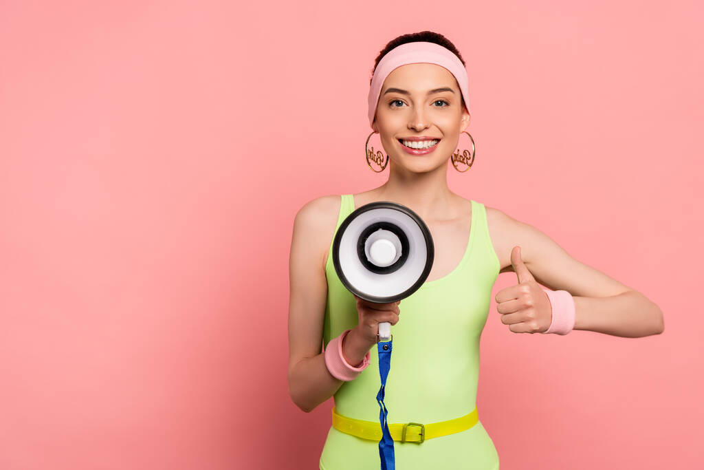 happy young woman showing thumb up and holding loudspeaker on pink  - Photo, Image