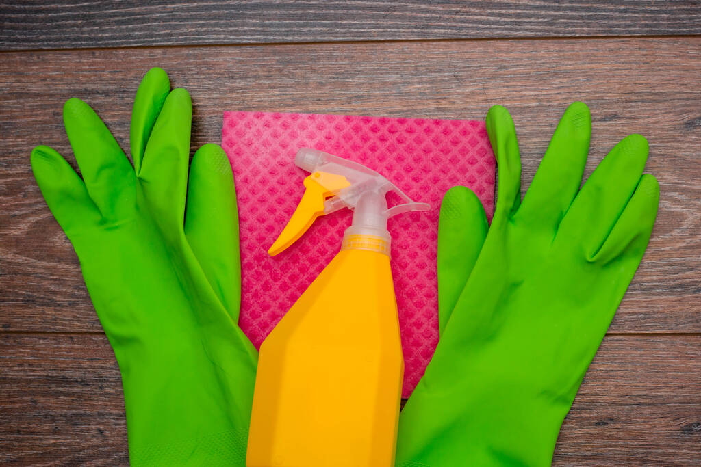 Close-up van een spuitfles, rubberen handschoenen en een natte doek op de vloer. Het concept van desinfectie van gebouwen, de preventie van virale en bacteriële ziekten. Reiniging van houten oppervlakken. - Foto, afbeelding