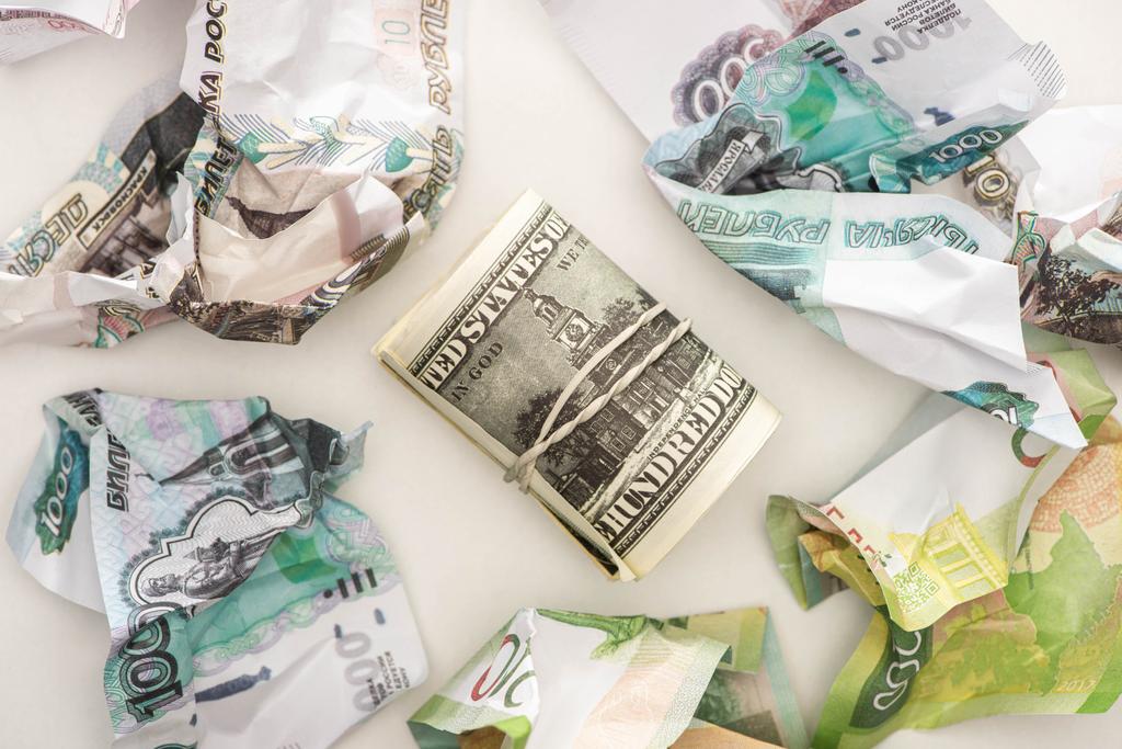 vista superior do rolo de dinheiro com dólares perto de notas de rublo amassadas isoladas em branco
 - Foto, Imagem