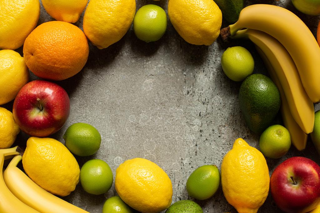 bovenaanzicht van smakelijke kleurrijke vruchten op grijs betonnen oppervlak - Foto, afbeelding