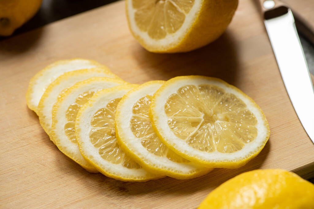 крупним планом вид нарізаного лимона на дерев'яній обробній дошці з ножем
 - Фото, зображення