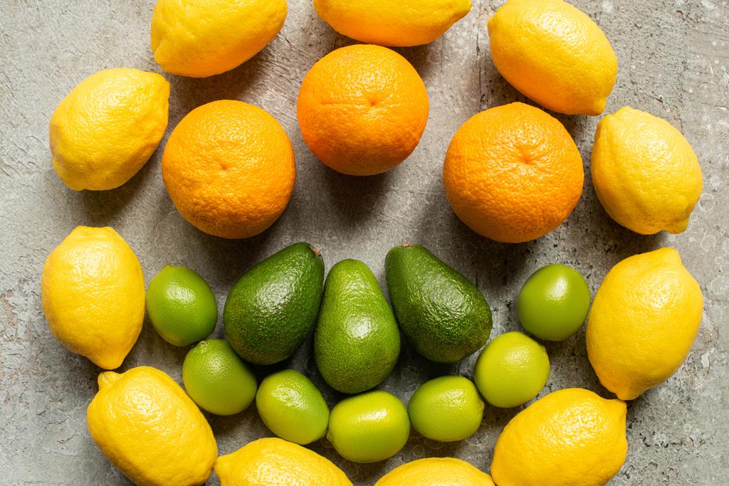 вид сверху на красочные апельсины, авокадо, лаймы и лимоны, расположенные по кругу на серой бетонной поверхности
 - Фото, изображение