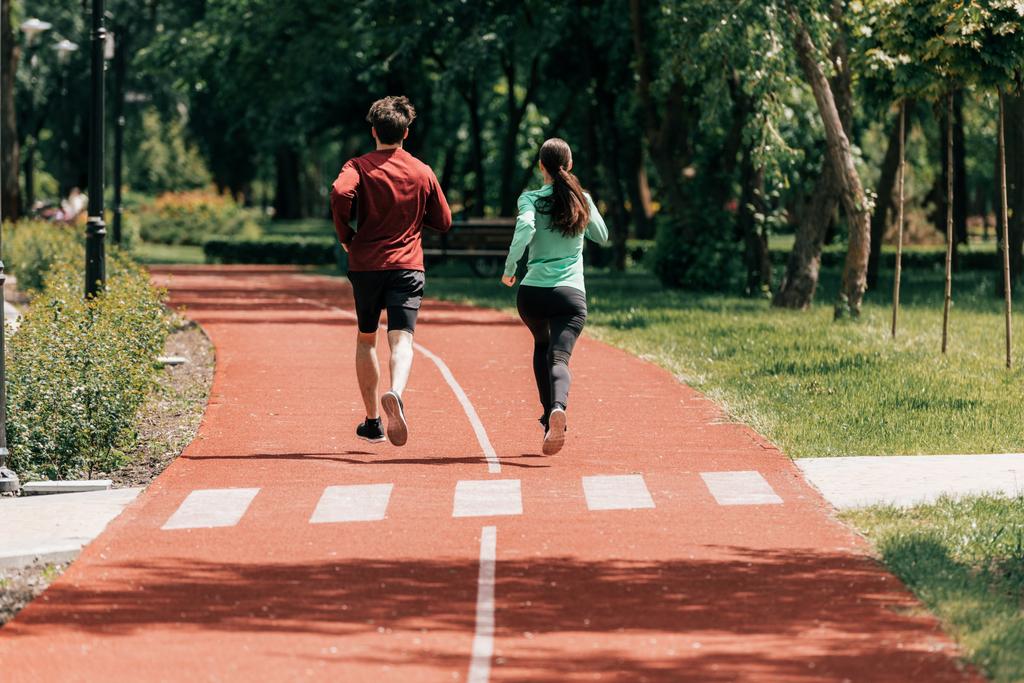 Genç bir çiftin parkta koşu parkurunda birlikte koşuşunun arka planı  - Fotoğraf, Görsel