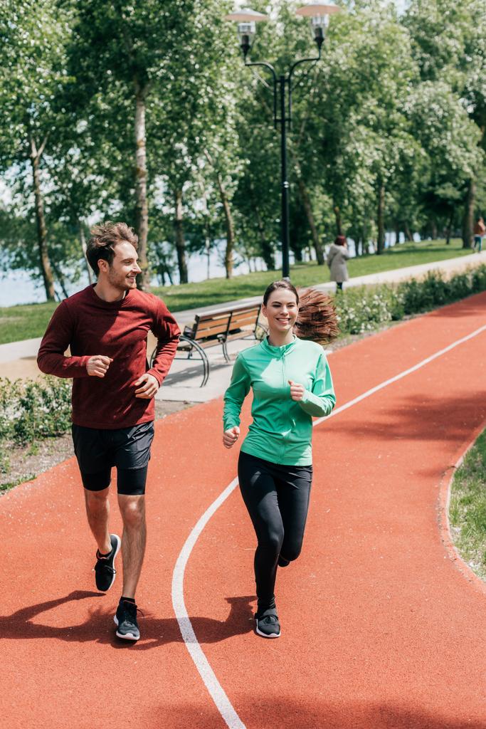 Hezký muž usmívá blízké přítelkyně během jogging v parku  - Fotografie, Obrázek