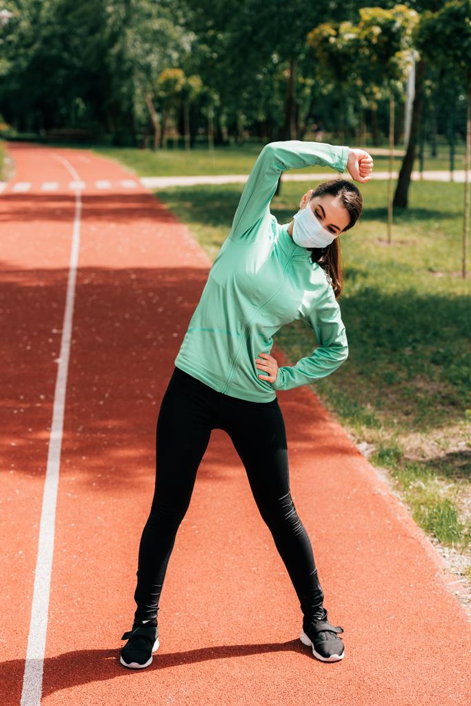 Sportovní žena v lékařské masce cvičení v parku ve dne  - Fotografie, Obrázek