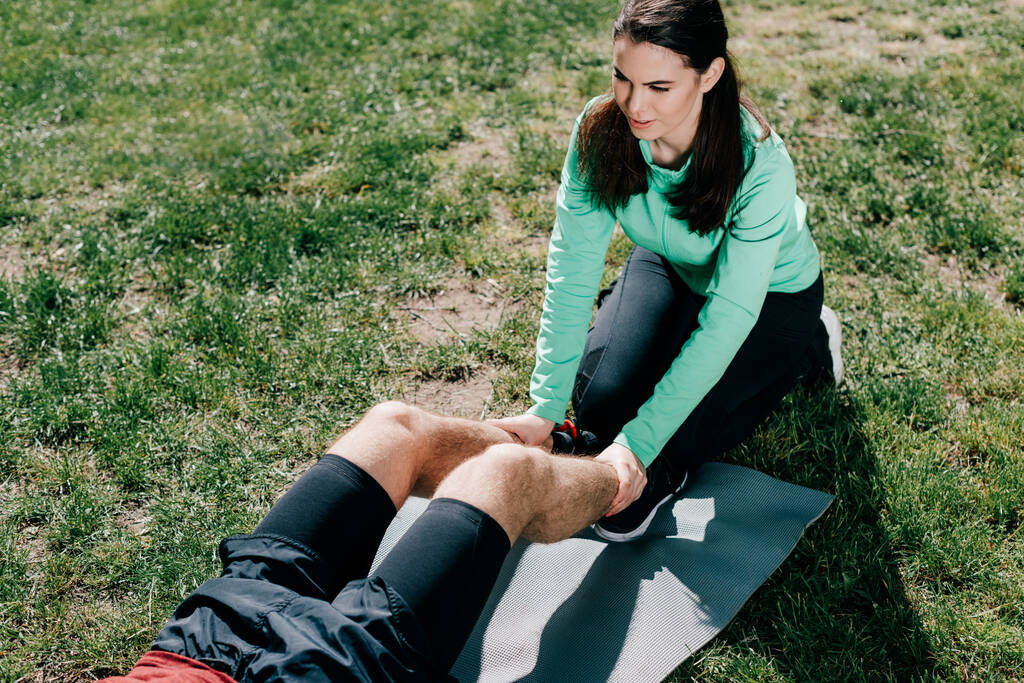 Vysoký úhel pohledu na atraktivní sportovkyně podporující sportovce při cvičení v parku  - Fotografie, Obrázek
