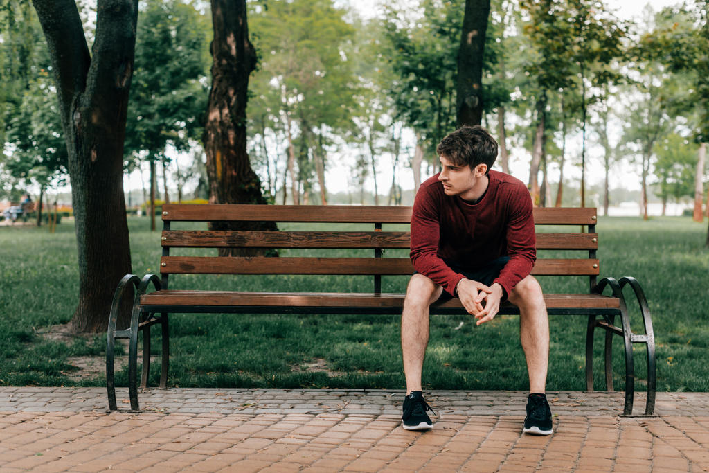 Hezký sportovec sedí na lavičce v parku  - Fotografie, Obrázek