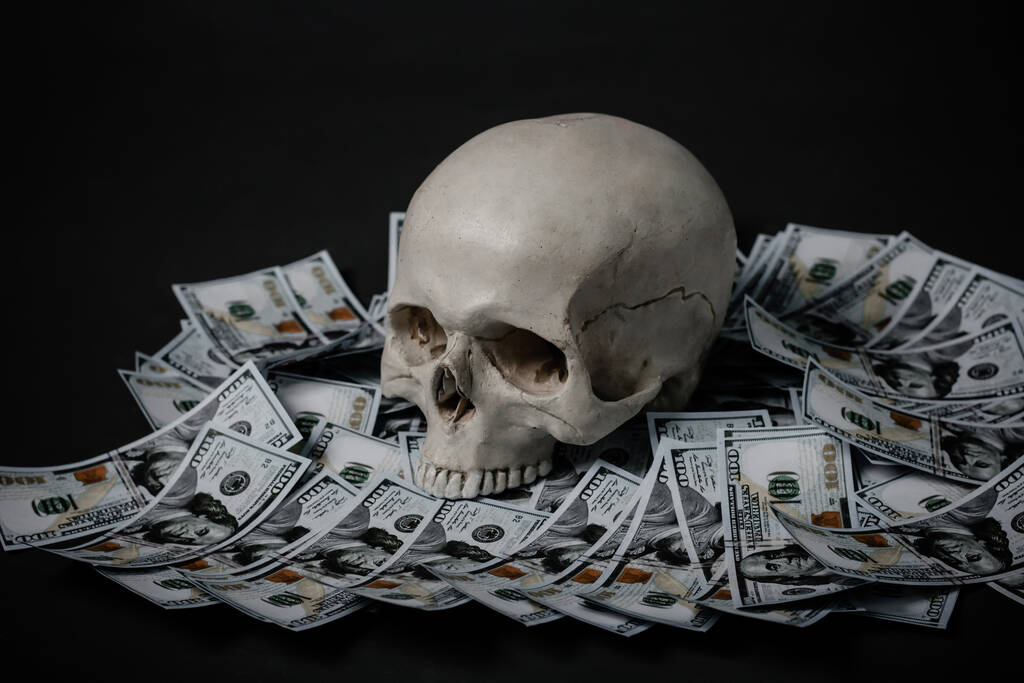 A human skull lies in the dark on money. - Photo, Image