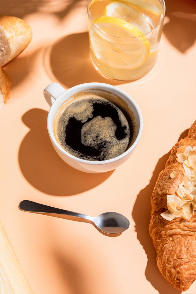 Kahvaltı için bej masada kahve, su ve kruvasan. - Fotoğraf, Görsel