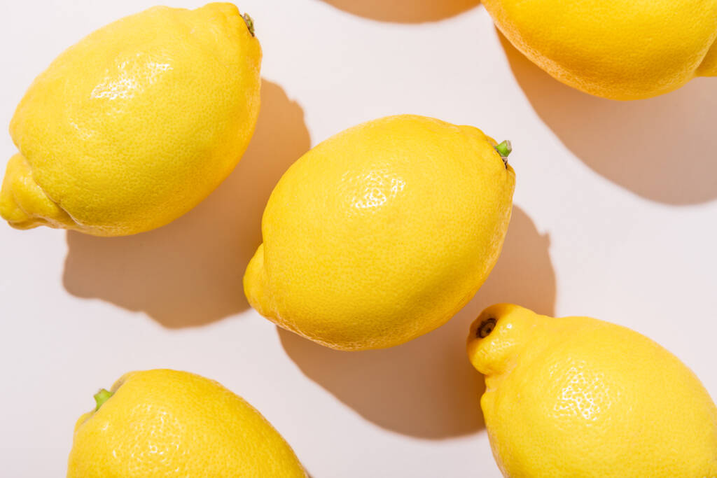 zavřít celé zralé citrony na šedém stole se stíny - Fotografie, Obrázek