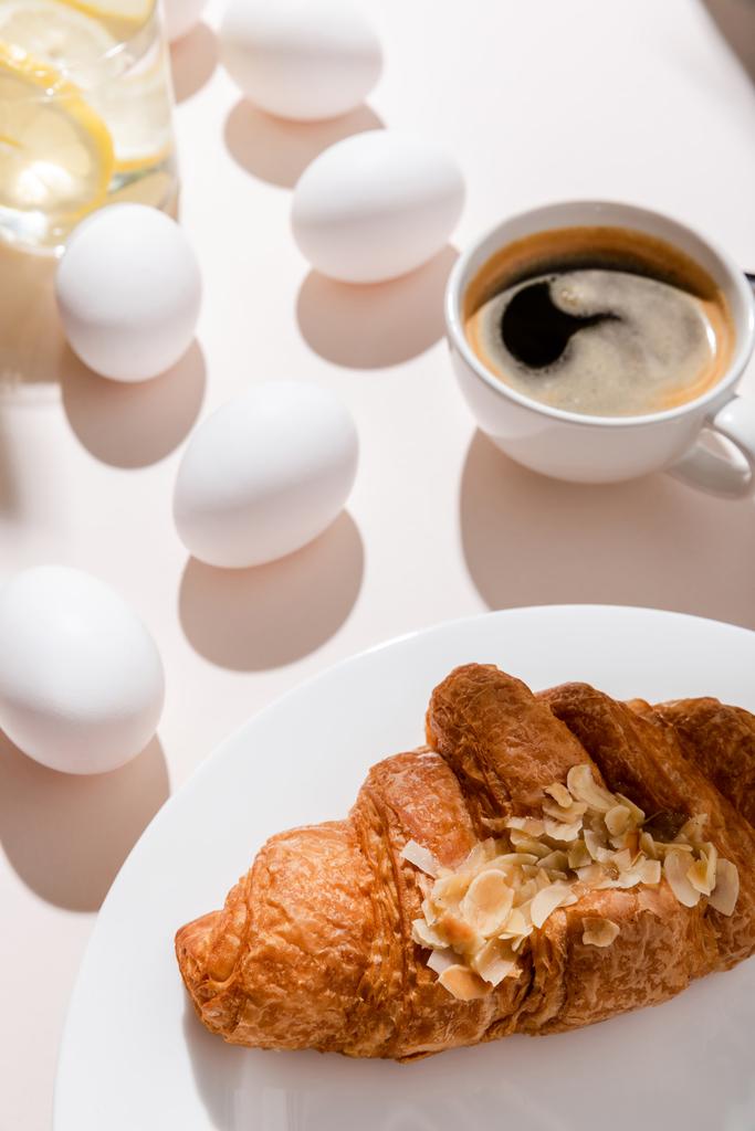 яйця, круасан, кава і вода з лимоном на сніданок на сірому столі з тінями
 - Фото, зображення