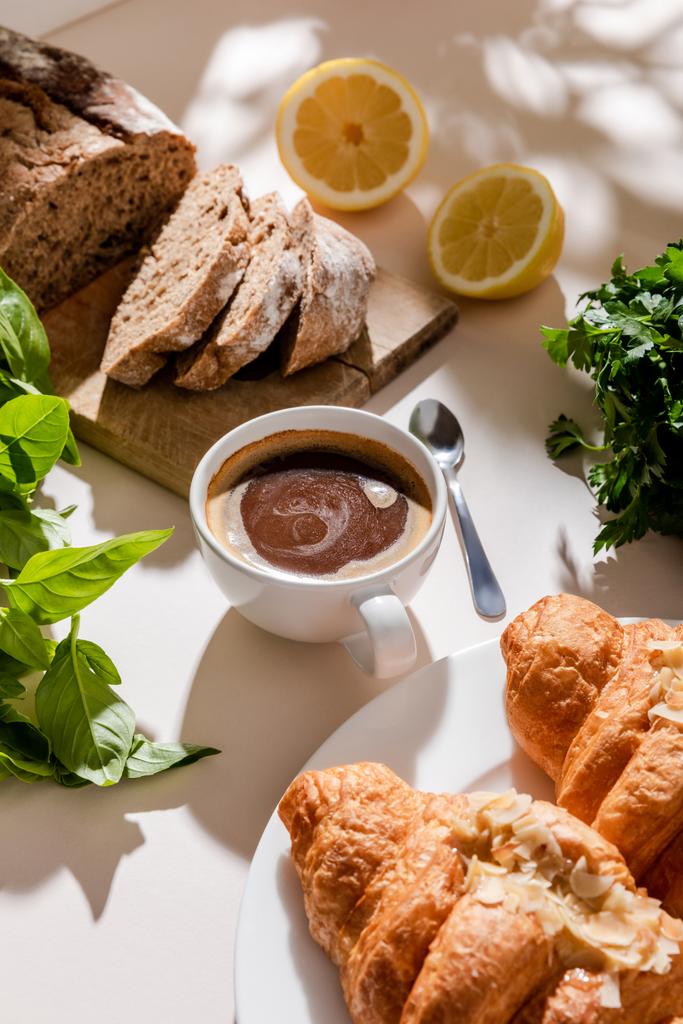 friss croissant, kenyér, zöldség és egy csésze kávé reggelire szürke asztalon   - Fotó, kép