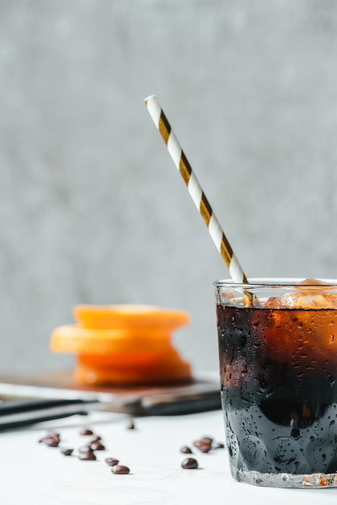 selective focus of cold brew coffee with ice and drinking straw on white table - Valokuva, kuva