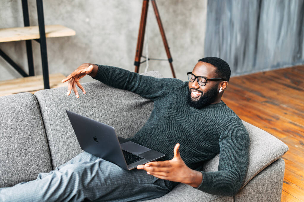 African-American guy lays on sofa with laptop - Photo, Image
