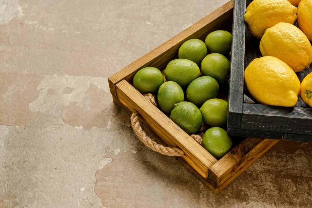 dojrzałe cytryny i limonki w drewnianych pudełkach na powierzchni wietrzonej - Zdjęcie, obraz