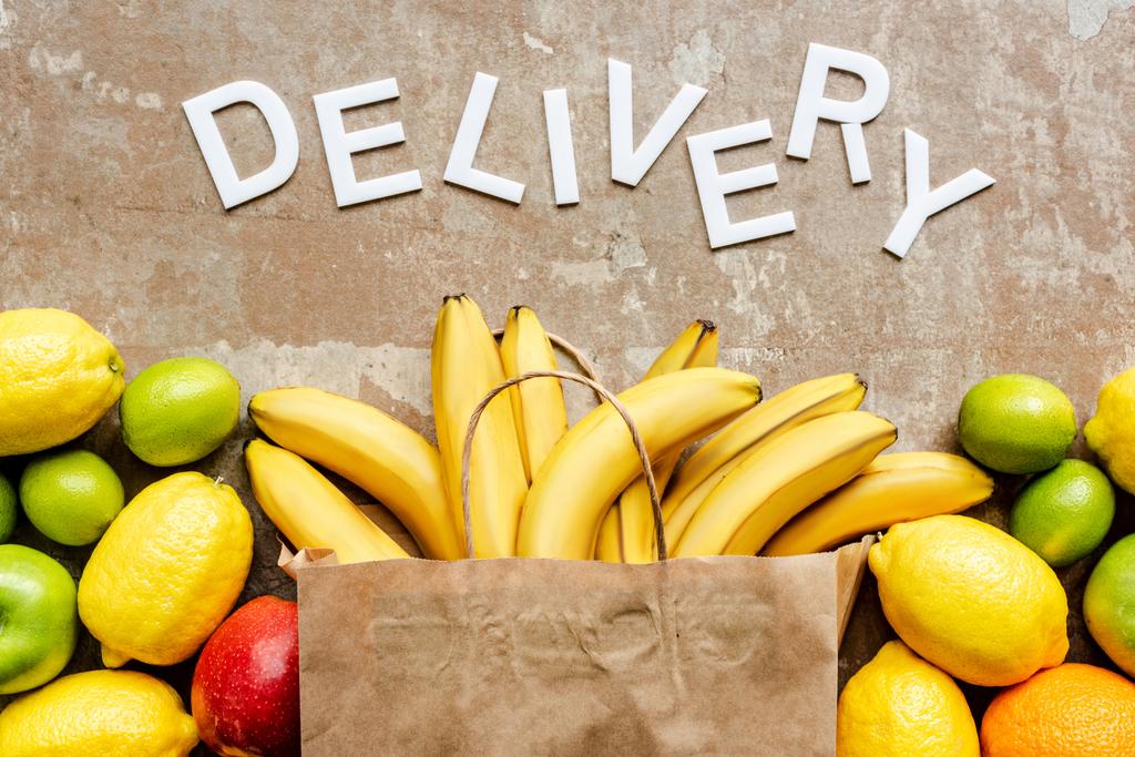 vista superior de la entrega de palabras cerca de la bolsa de papel con frutas frescas de colores en la superficie envejecida beige
 - Foto, imagen