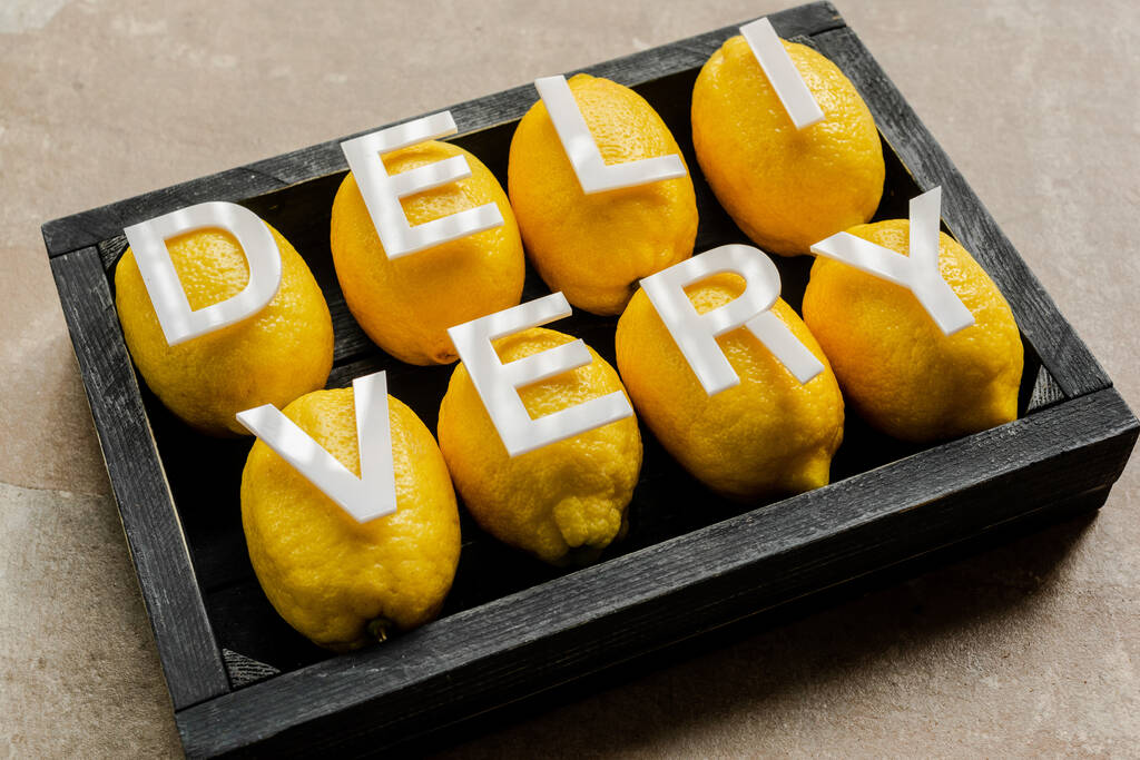 woord levering op citroenen in houten zwarte doos op verweerd oppervlak - Foto, afbeelding