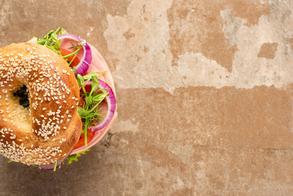 top view of fresh delicious bagel with sausage on aged beige surface - Photo, Image
