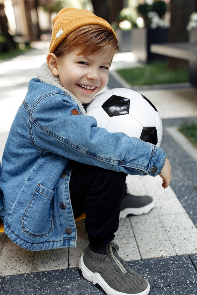 Foto de menino bonito posando com bola de futebol na rua
. - Foto, Imagem