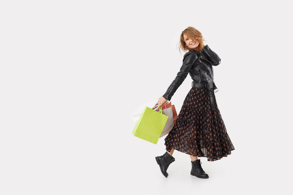 Jovem com sacos de compras faz compras através do aplicativo on-line em um smartphone
 - Foto, Imagem