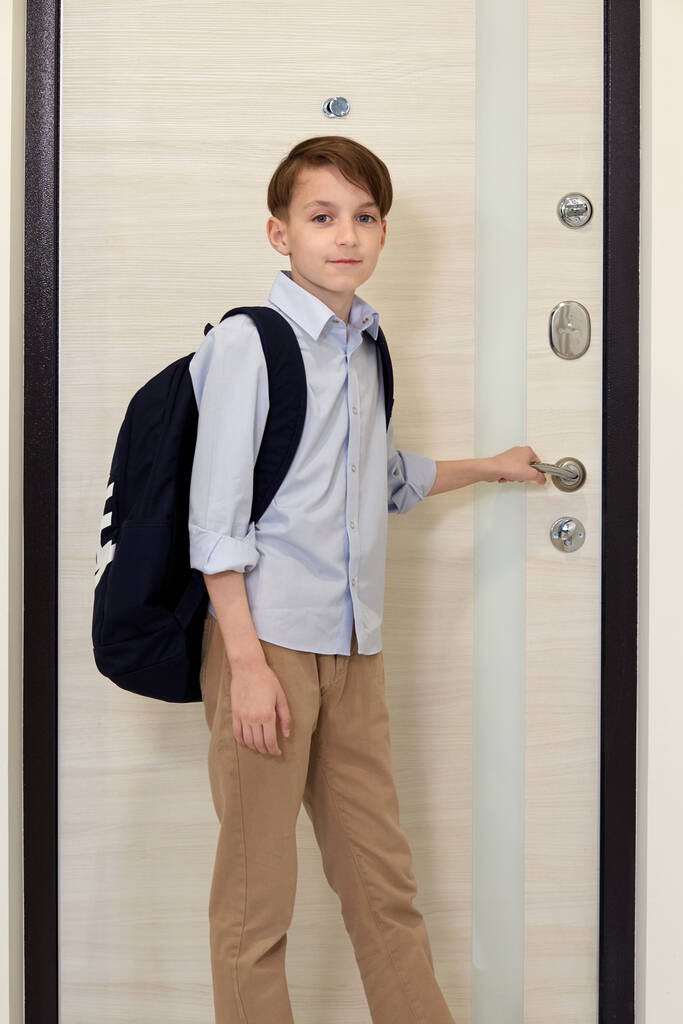 Um rapaz bonito de camisa azul com uma mochila nas costas vai para a escola.
. - Foto, Imagem