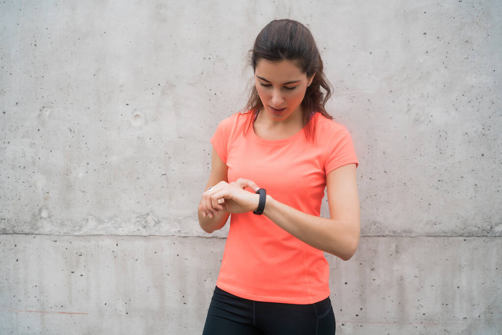 Retrato de una mujer de fitness comprobando el tiempo en su reloj inteligente. Concepto de deporte y estilo de vida saludable. - Foto, Imagen