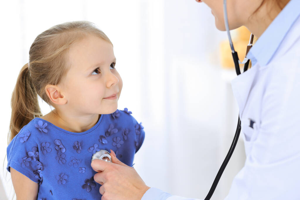 Arzt untersucht ein kleines Mädchen per Stethoskop. Glücklich lächelnder Kinderpatient bei der üblichen ärztlichen Untersuchung. Medizin- und Gesundheitskonzepte - Foto, Bild