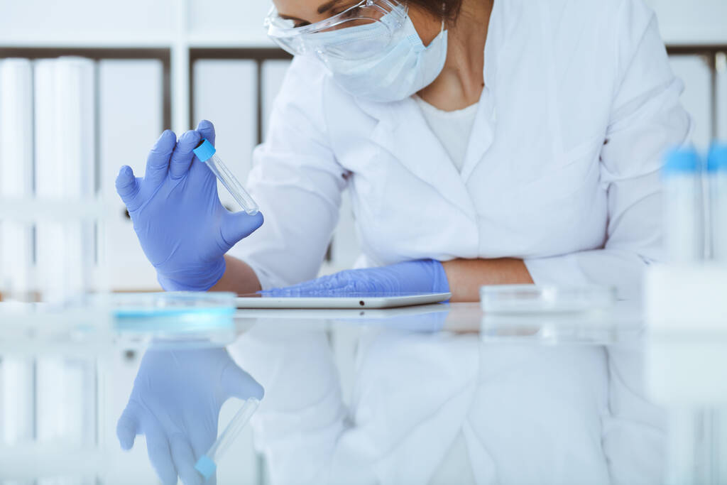 Profi női tudós közelkép védőszemüvegben kísérletezik reagensekkel a laboratóriumban. Orvosi és kutatási koncepció - Fotó, kép