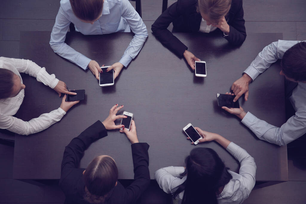 Liikemiehet tyhjiä puhelimia istuu pöydän ympärillä sovelluksen, ylhäältä - Valokuva, kuva