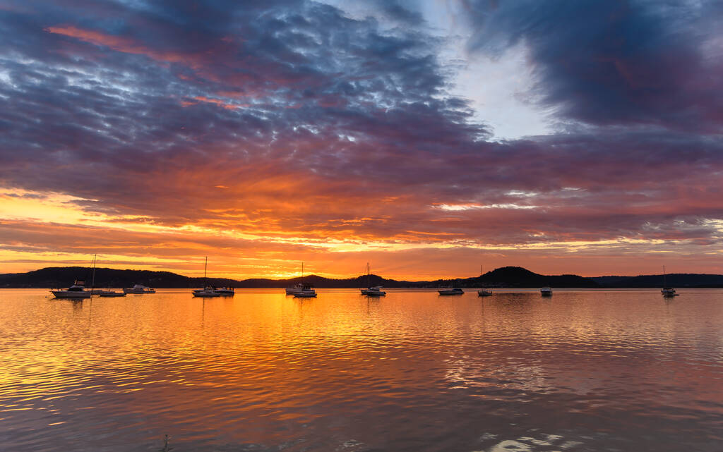 Dramatische Wasserlandschaft bei Sonnenaufgang mit Wolken und Booten am Koolewong Foreshore, Koolewong, Central Coast, NSW, Australien - Foto, Bild