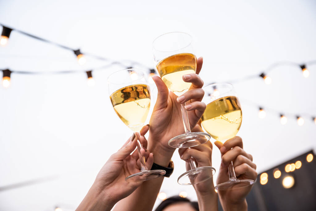 Група людей на вечірці і святкує разом з білим вином і пивом. Щасливі азіати люблять гуляти на фестивалі і святкувати з білим вином на даху бару і ресторану.. - Фото, зображення